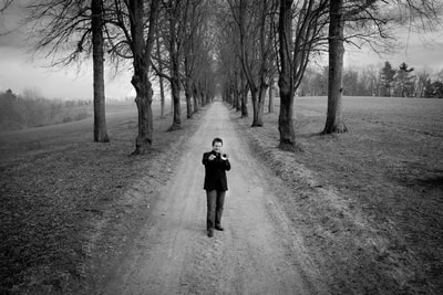 Trumpeter Doug Woolverton is photographed by fine art photographer David Lee Black on a tree lined road in Massachusetts. 